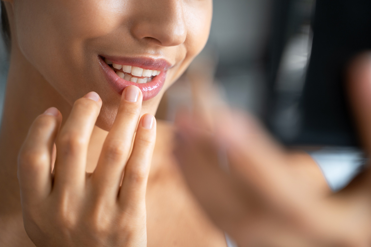 Pleased young woman applying a lip balm